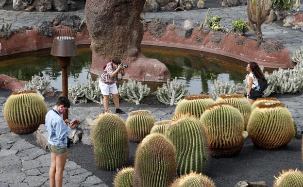 Arriba, un trabajador turístico en Gando; José María Mañaricua y Jorge Marichal. Debajo, imagen de turistas en el Jardín de Cactus de Tahíche, en Lanzarote. / CARRASCO