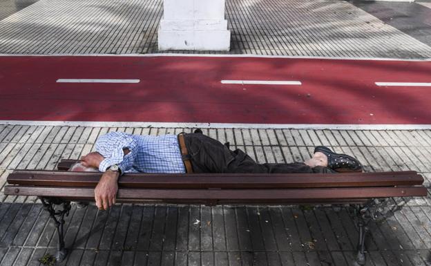 Una persona sin hogar duerme en un banco en el entorno de Santa Catalina de la capital grancanaria. 