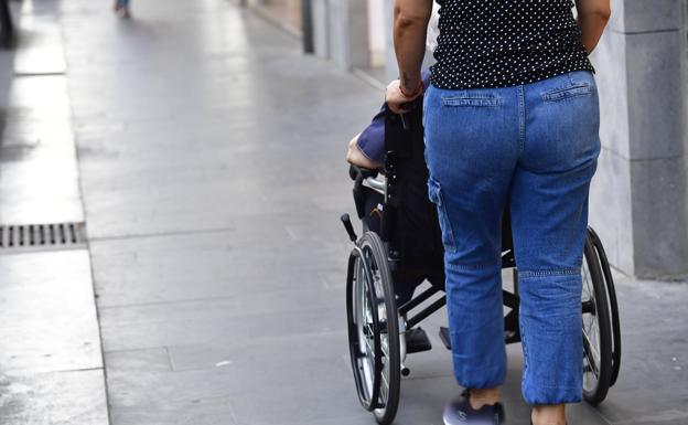 Imagen de archivo sin relación con esta información. Una mujer pasea a una persona mayor en silla de ruedas. 