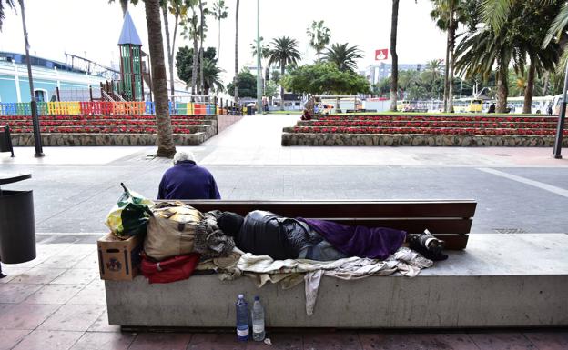 Una persona sin techo duerme en banco del parque de Santa Catalina. 