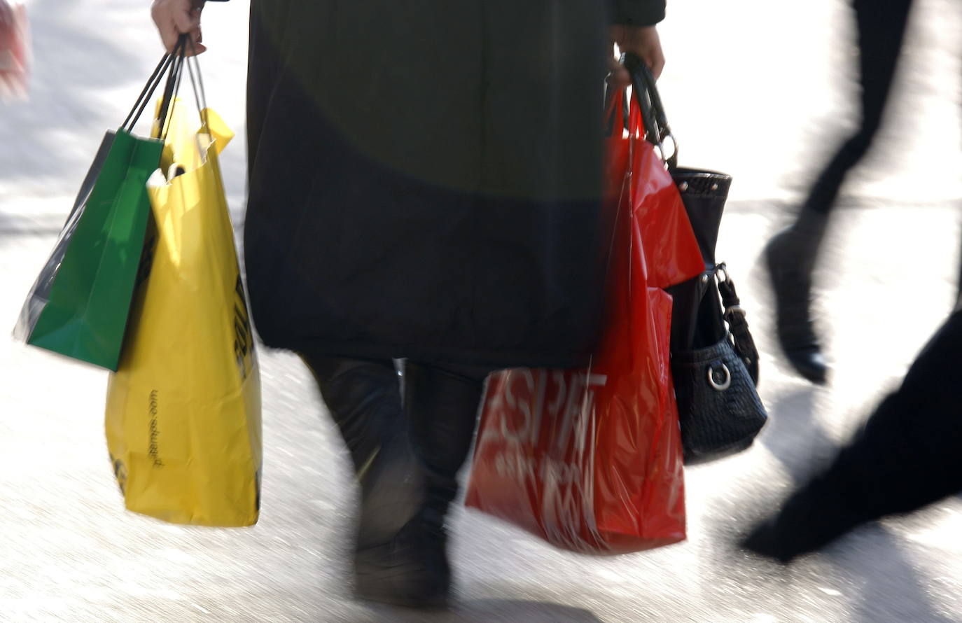 Una mujer camina con una bolsa de compras. 