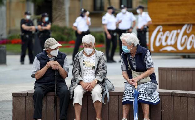 Unos ancianos conversan protegidos con mascarillas. /Efe