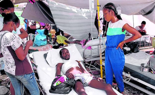 Un herido es asistido en una tienda de campaña improvisada levantado junto a las instalaciones del hospital general de Los Cayos, muy dañado por el terremoto.