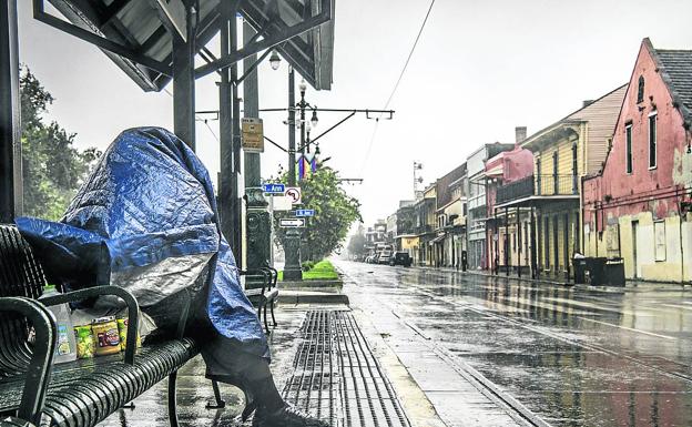 Una persona se protege de las lluvias previas a la llegada del 'Ida' en una parada de tren de Nueva Orleáns./AFP