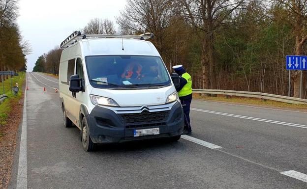 Un policía controla documentación de un vehículo en la carretera que une la localidad polaca de Sokólka y la de Kuznica, en la frontera con Bielorrusia.