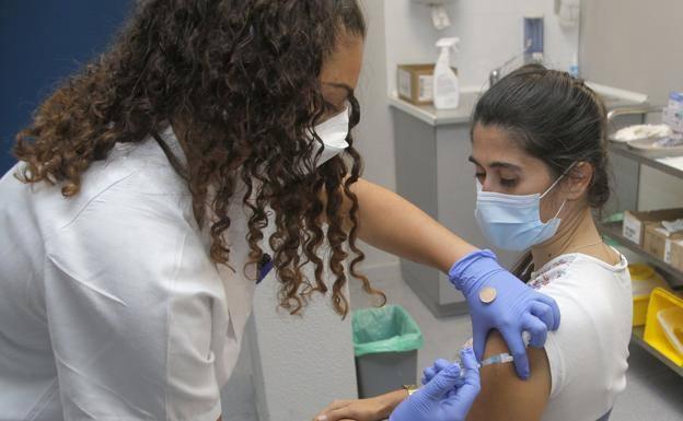 La vacunación de los grupos más jóvenes va más adelantada en las islas no capitalinas. En la imagen una sanitaria vacuna a una joven en Lanzarote. /Carrasco