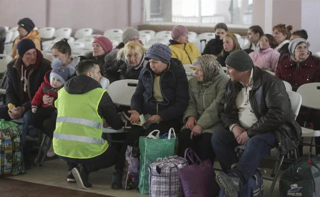 A volunteer helps a group of refugees at the Odessa station.  /EFE