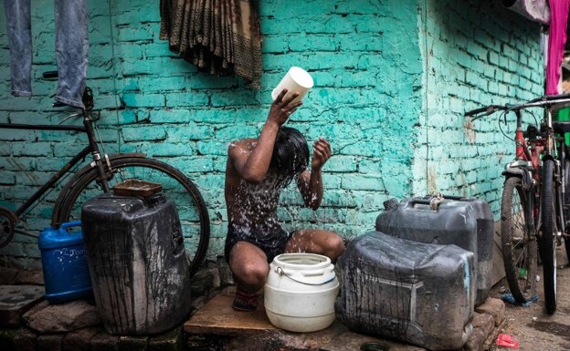 Un joven se refresca en las calles de Nueva Delhi azotada por temperaturas extremas en mayo. /AFP