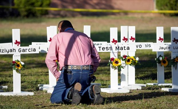Duelo. El pastor Daniel Myers ora frente a las cruces funerarias de las víctimas de la masacre en la escuela primaria de Robb.