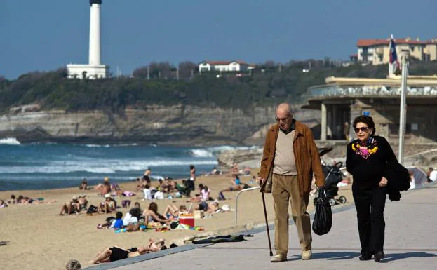 Two retirees walking along a beach. 