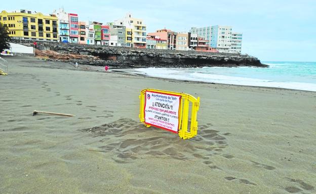 Cartel y valla con los que el Ayuntamiento informó ayer del cierre al baño de la playa de La Garita. / C7