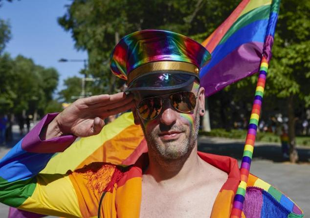 Un participante hace el saludo militar ataviado con los colores arco iris. 