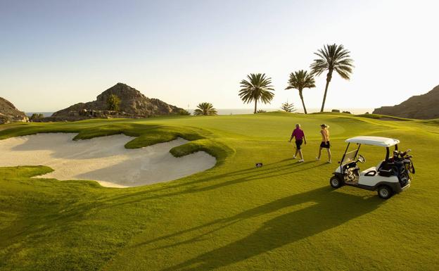 Two golfers enjoy the garden of Anfi Tauro Golf at sunset 