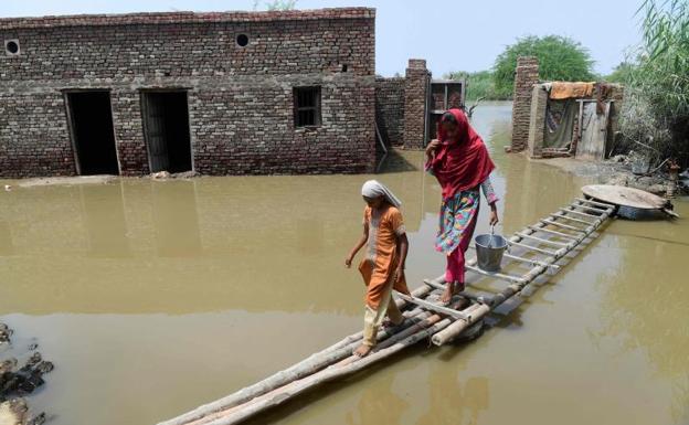 Una mujer y una niña tratan de cruzar las calles inundadas del poblado de Shikarpur . /Asif HASSAN / AFP