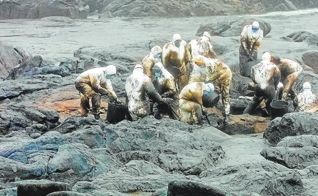Imagen de voluntarios y expertos colaborando en las labores de limpieza en la costa gallega tras el hundimiento del petrolero en noviembre de 2002. 